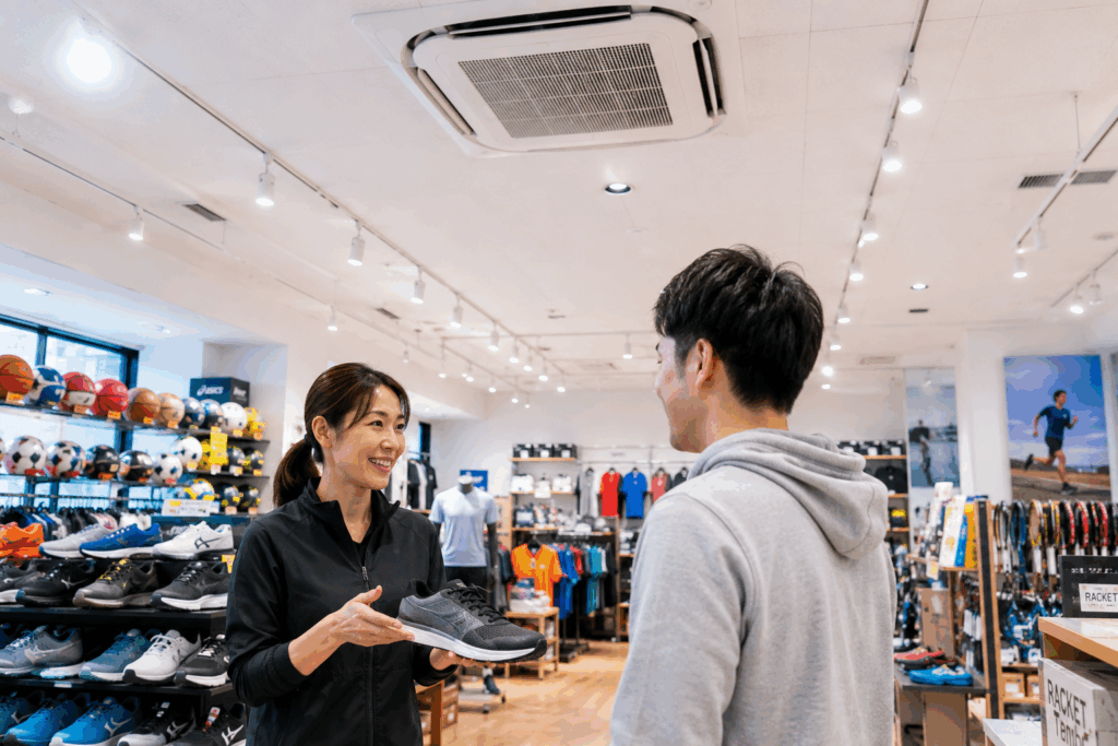 スポーツ用品店で接客を行う女性店主と顧客、天井埋込型業務用エアコン