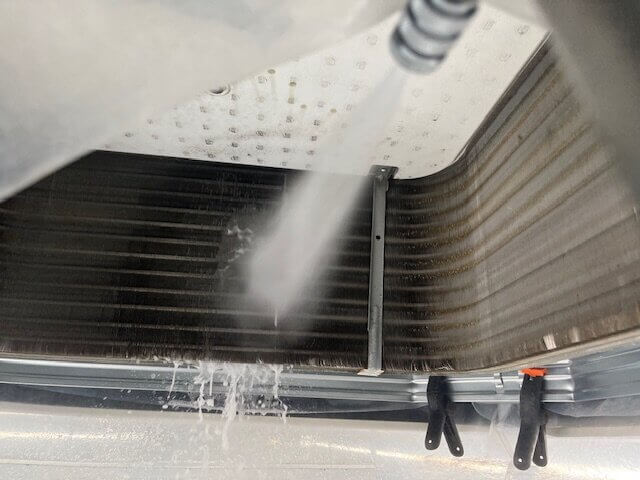 福岡市で業務用エアコン内部の熱交換器を高圧洗浄している様子