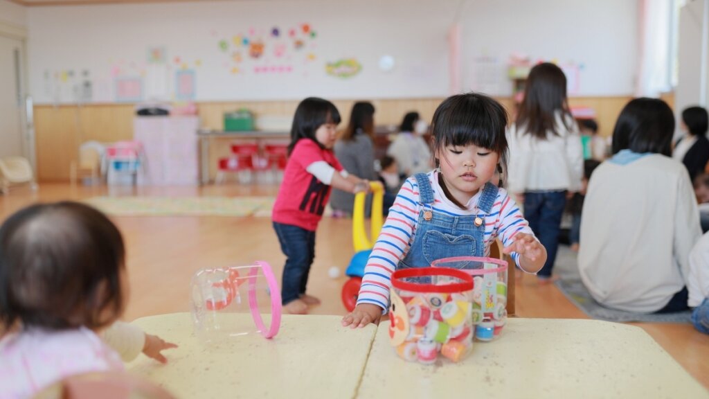 幼稚園の教室で遊びながら過ごす子どもたちと保育スタッフ