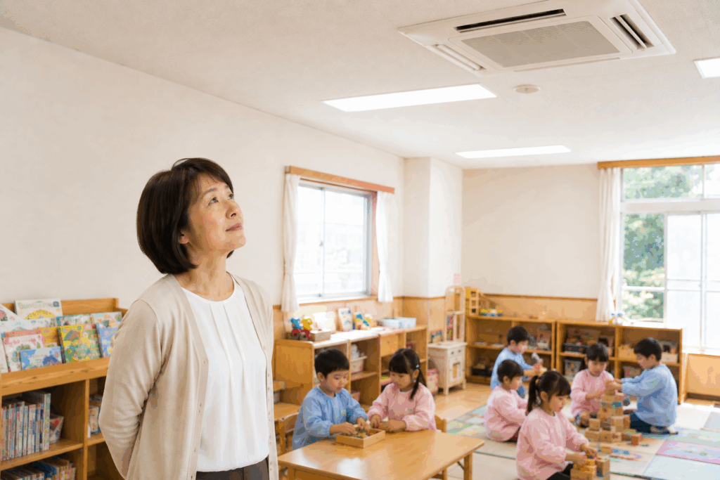 園児が過ごす教室で天井の業務用エアコンを気にする女性園長